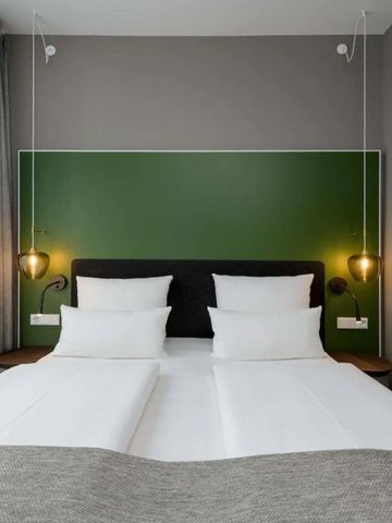 Komfortables Hotelzimmer mit einem großen Bett und grüner Akzentwand