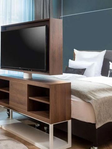 Hotelzimmer mit Doppelbett und modernem Fernseher auf einem Holzgestell