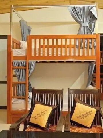 Zimmer mit Etagenbett aus Holz und gepolsterten Stühlen