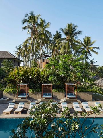 Swimmingpool umgeben von Palmen und Holzmöbeln für sonnige Tage