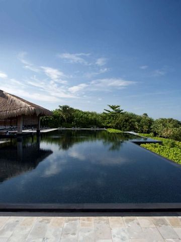 Infinity Pool mit Palmen und Meerblick unter klarem blauen Himmel