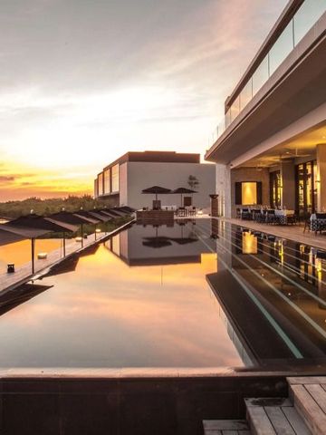 Infinity Pool bei Sonnenuntergang mit modernen Gebäuden im Hintergrund