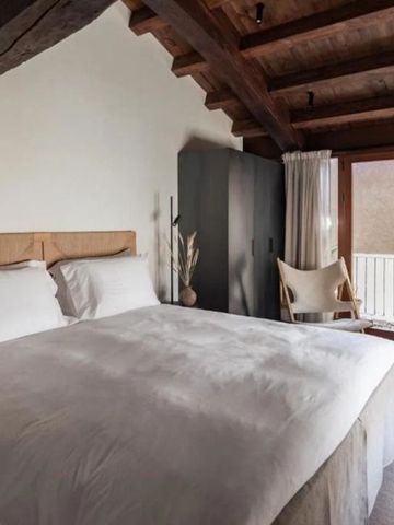 Gemütliches Schlafzimmer mit Holzbalken und großen Fenstern mit Vorhängen