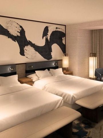 Hotelzimmer mit zwei Doppelbetten in sanften Farbtönen und stilvollem Dekor