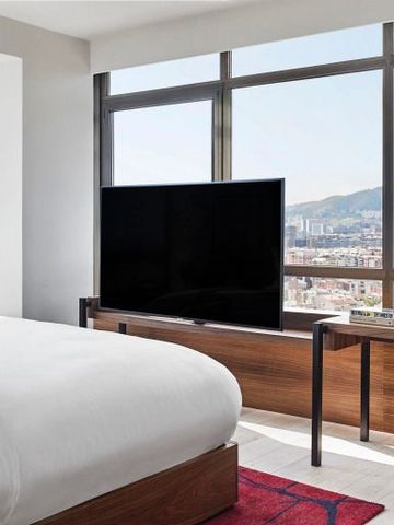 Großes Bett mit Fernsehblick und Panoramafenster im Hotelzimmer