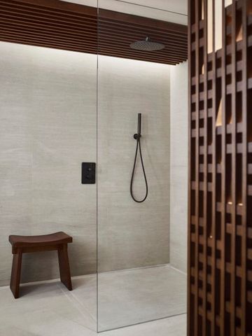 Moderne Dusche mit stilvollem Holzhocker im Hotelbad