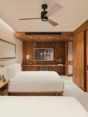 Elegantes Hotelzimmer mit zwei Betten, Holzverkleidung und stilvoller Dekoration.