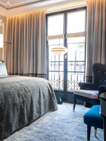 Elegantes Hotelzimmer mit Doppelbett, blauen Vorhängen und stilvoller Beleuchtung