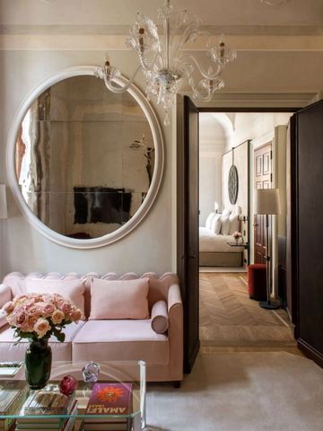 Stilvolles Wohnbereich im Hotelzimmer mit runder Wanddekoration und rosa Sofa.