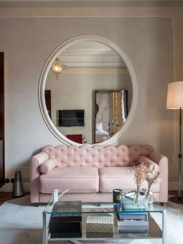 Elegantes Wohnzimmer mit rundem Spiegel und rosa Sofa in luxuriöser Suite