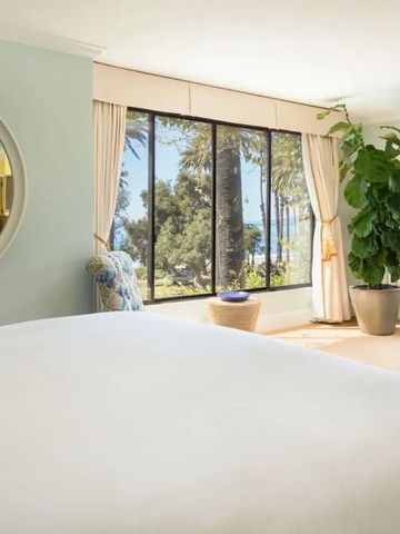 Helles Zimmer mit großen Fenstern und Blick auf Palmen