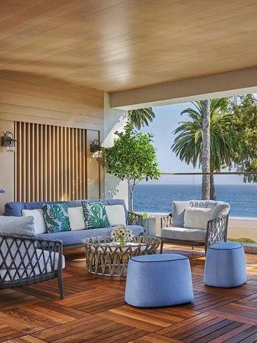 Terrasse mit gemütlichen Sitzgelegenheiten und Blick auf Palmen und Meer