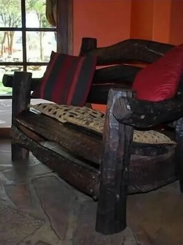 Gemütliches Wohnzimmer mit rustikalen Holzsesseln und roten Akzenten