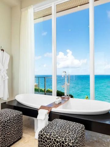 Badezimmer mit Panoramafenster und Badewanne mit Meerblick.