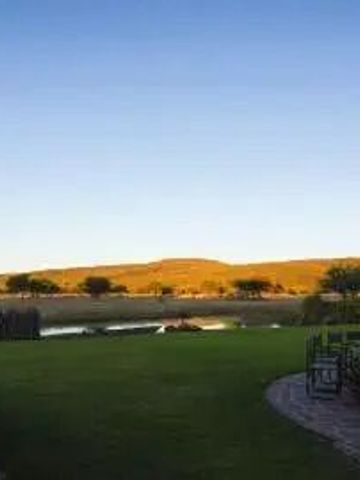 Weitläufiger Blick auf die grüne Landschaft mit einem Wasserloch in der Ferne