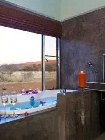 Luxuriöses Badezimmer mit Badewanne, Fenster mit Blick auf die Natur und Sektgläsern.