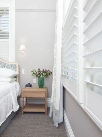 Helles Gästezimmer mit weißen Fensterläden und floraler Dekoration