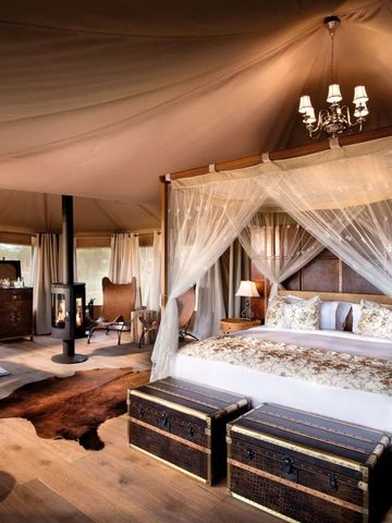 Großes Bett mit Baldachin in einem geräumigen Safari-Zelt mit Holzmöbeln