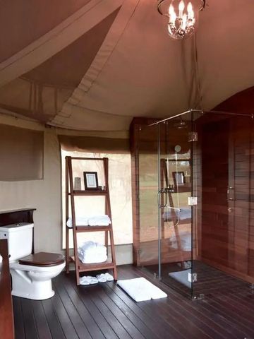 Modernes Badezimmer in einem Safari-Zelt mit Glasdusche und edlen Holzelementen