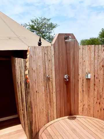 Außendusche aus Holz neben einem luxuriösen Zelt