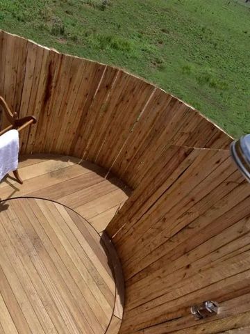 Rundum geschlossene hölzerne Außendusche mit Blick in die Natur