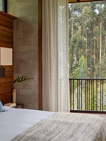 Gemütliches Schlafzimmer mit Holzelementen und Blick auf grüne Bäume