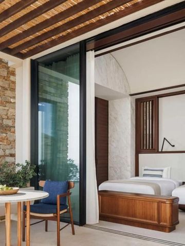 Hotelzimmer mit zwei Betten, rustikale Steinwand und Sitzbereich auf Balkon.