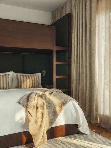 Helles Schlafzimmer mit großem Bett und weichen Textilien neben bodenlangen Vorhängen.