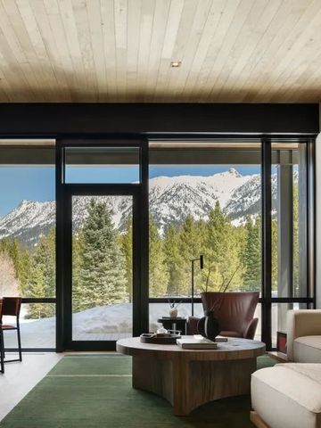 Modernes Wohnzimmer mit großer Fensterfront und Blick auf verschneite Berge