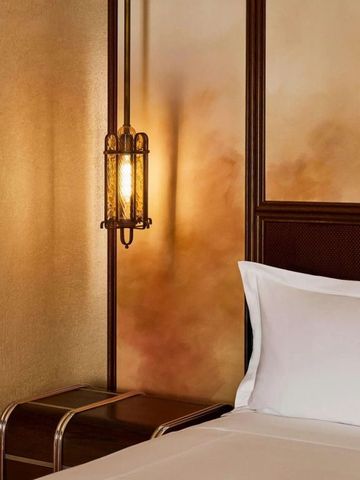 Detail einer stilvollen Beleuchtung neben einem gemütlichen Bett