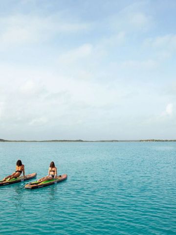 Zwei Personen beim Paddeln auf ruhigem türkisfarbenem Wasser