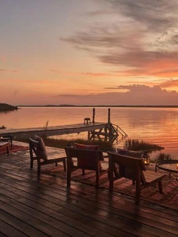 Sonnenuntergang über einem ruhigen See mit Holzmöbeln auf der Terrasse