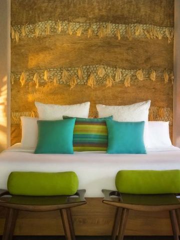 Farbenfrohes Bett mit natürlicher Wanddekoration