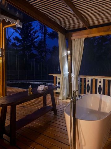 Freistehende Badewanne auf einer Terrasse bei Nacht mit Waldkulisse