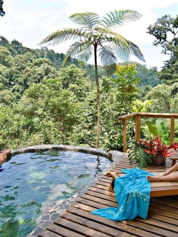 Zwei Personen entspannen am Infinity Pool mit Blick auf den Regenwald