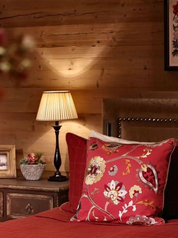 Gemütliches Hotelzimmer mit Holzwänden und dekorativem Kissen auf dem Bett