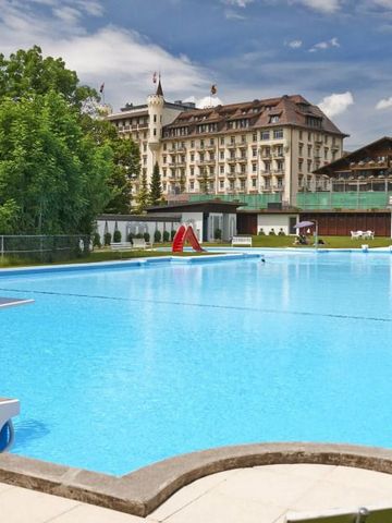 Großer Außenpool mit Blick auf das Gstaad Palace Hotel im Hintergrund