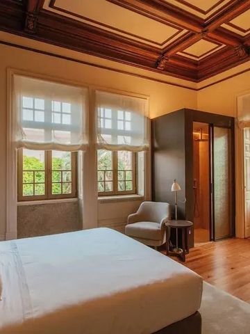 Elegantes Hotelzimmer mit stilvoller Holzdecke und großem Fenster mit Gartenblick