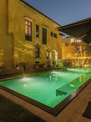 Beleuchteter Pool bei Nacht neben historischer Fassade des Hotels