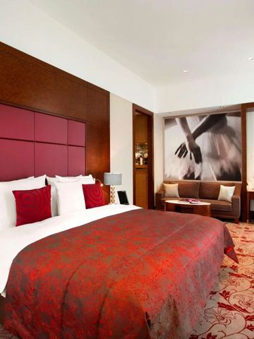 Hotelzimmer mit roter Bettdecke und stilvoller Kunst an der Wand.
