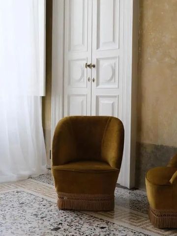 Eleganter Sitzbereich mit hellen Vorhängen und zwei samtigen Sesseln auf gemustertem Boden.