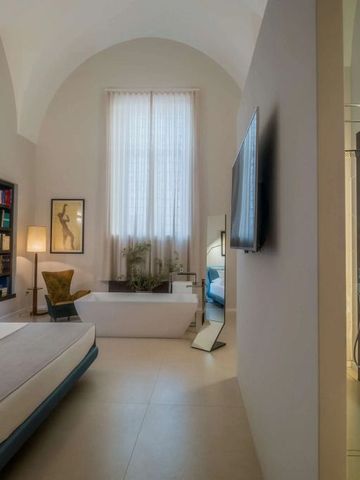 Modernes Schlafzimmer mit hohen Decken, großem Fenster und freistehender Badewanne