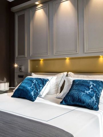 Nahaufnahme eines luxuriösen Bettes mit blauen Zierkissen und stimmungsvoller Beleuchtung.