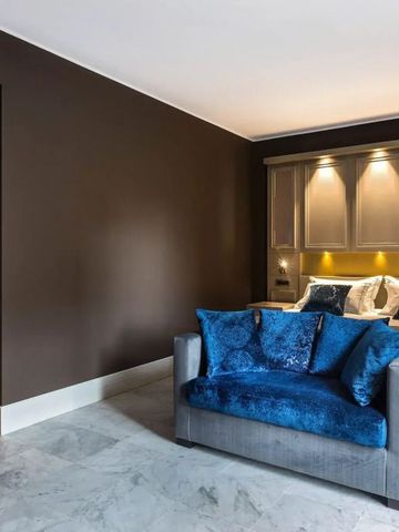 Hotelzimmer mit grauem Sofa, großen Kissen und angenehmem Ambiente.