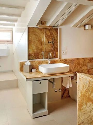 Helles Badezimmer mit Fenster und großzügiger Marmorverkleidung