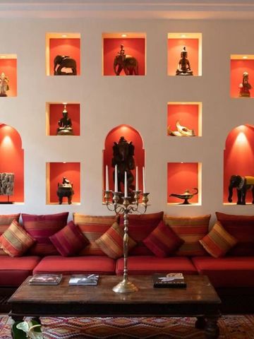 Gemütliche Lounge mit roten Kissen und kunstvollen Nischen mit Skulpturen