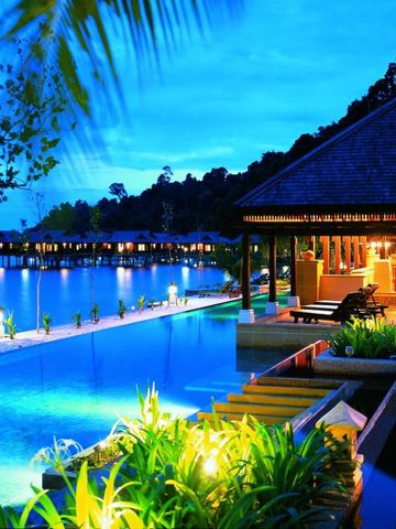 Beleuchteter Infinity Pool mit Meerblick bei Dämmerung