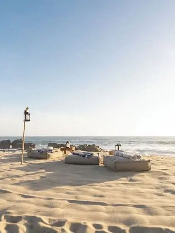 Sandige Strandlandschaft mit bequemen Liegen und Meerblick bei Sonnenschein