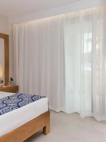 Schlichtes Hotelzimmer mit großen Fenstern und Gartenblick