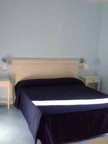 Zimmer mit Doppelbett, blauer Tagesdecke und weißen Nachttischen